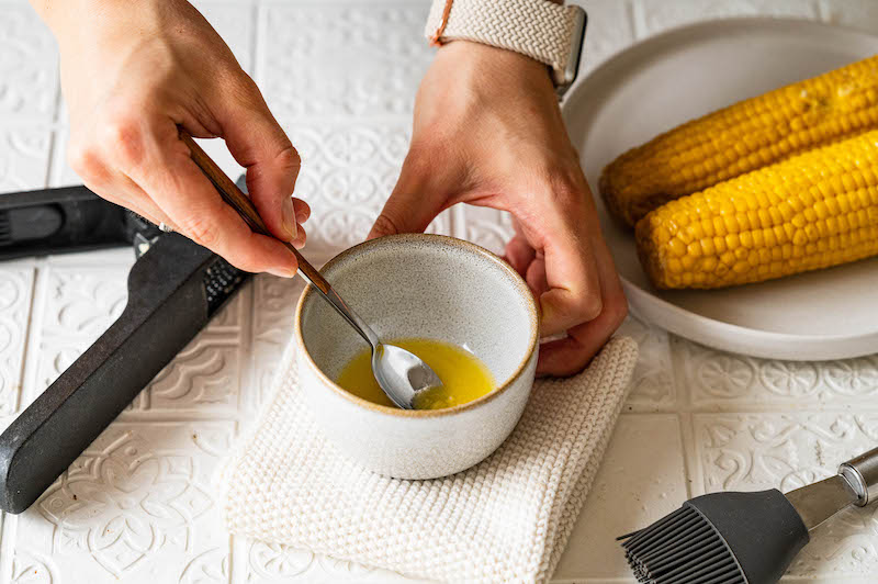 Flüssige Butter und gepresster Knoblauch werden in einer Schüssel verrührt.