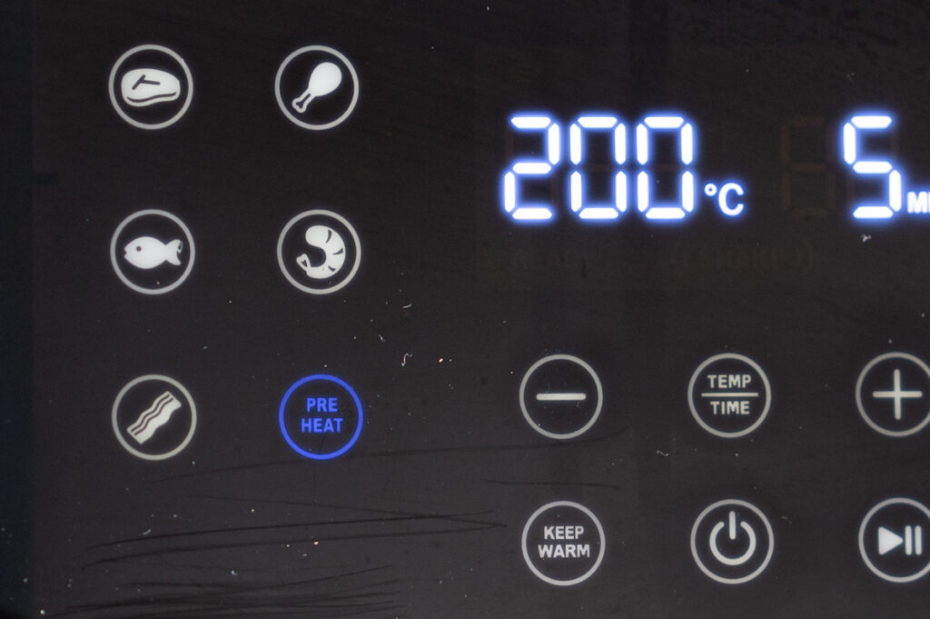 Display einer Heißluftfritteuse bzw. Airfryer, auf welchem der Vorheizen Knopf blau aufleuchtet.