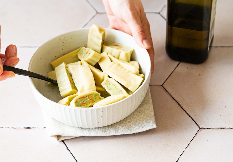 Maultaschen Stücke werden in einer Schüssel mit Öl vermengt.