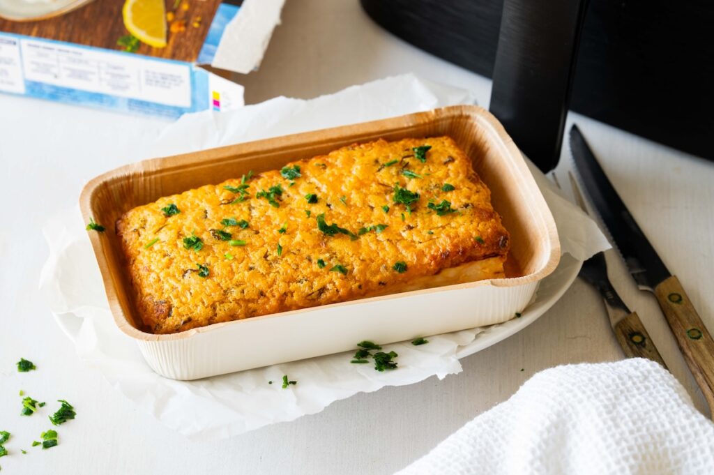 Schlemmerfilet in der Pappschale auf einem Teller in der Heißluftfritteuse zubereitet.